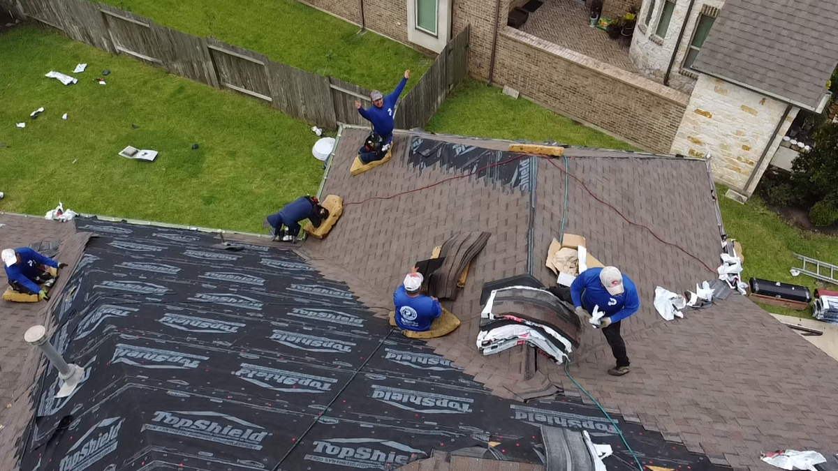 Roofers completing a roof replacement.