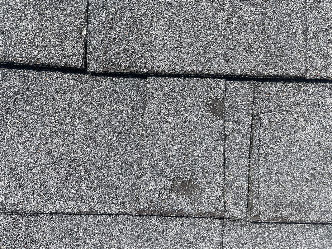 Close-up of asphalt roof shingles showing subtle surface marks.