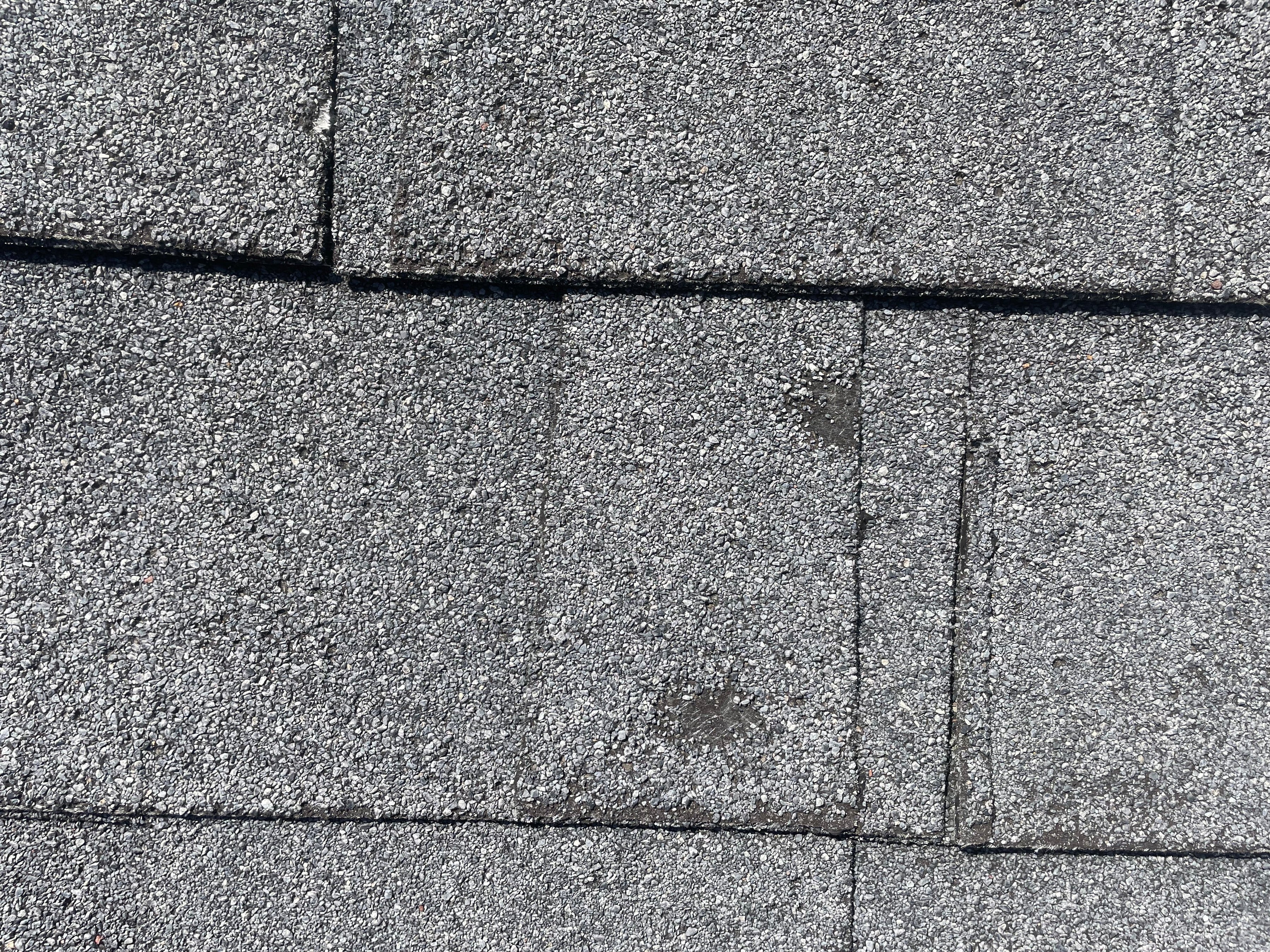 Close-up of asphalt roof shingles showing subtle surface marks.