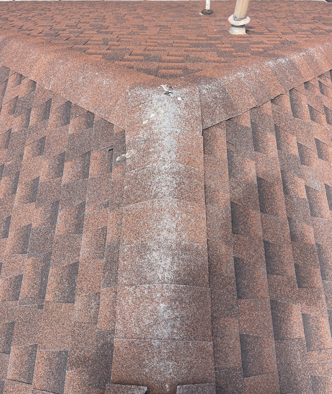 Close-up of roof ridge shingles showing subtle wear and granule loss.
