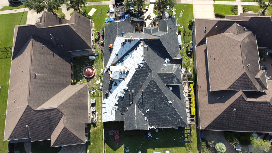 Aerial view of a residential home with roofing materials and underlayment visible during a roof replacement process in a Texas neighborhood.