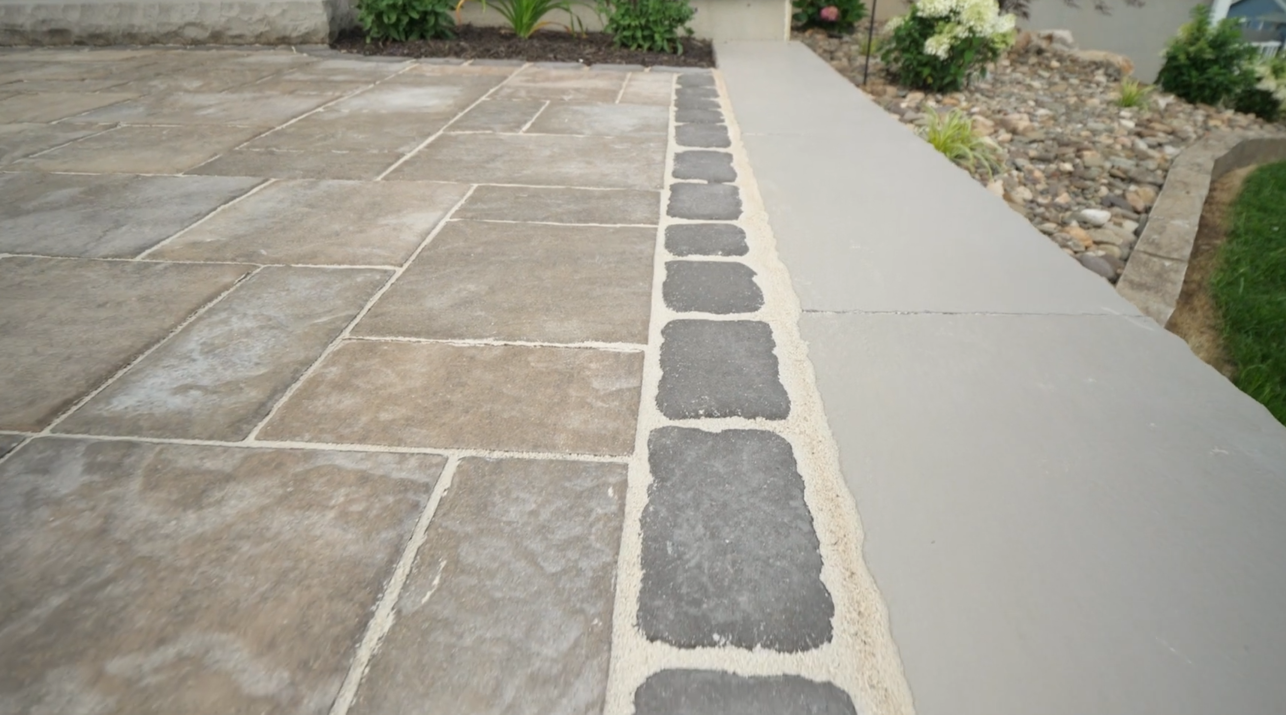 Close-up of stone and concrete paver walkway showing textured hardscape surface in a residential setting.