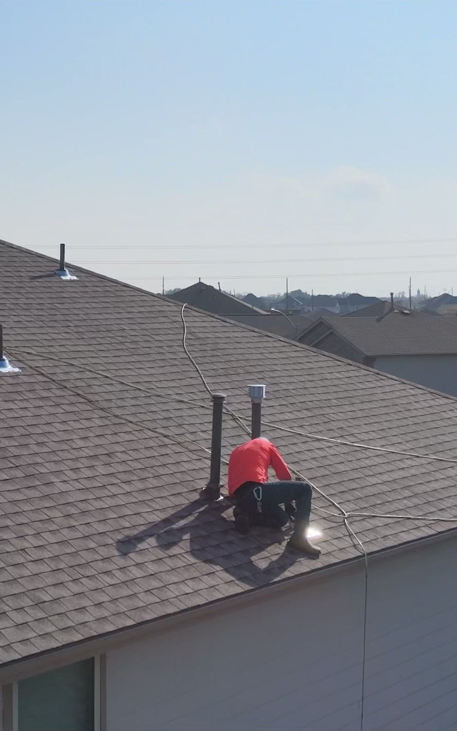 Load Video: Aerial view of a residential roofing project in Houston showing a newly completed asphalt shingle roof by Prime Property Builders.